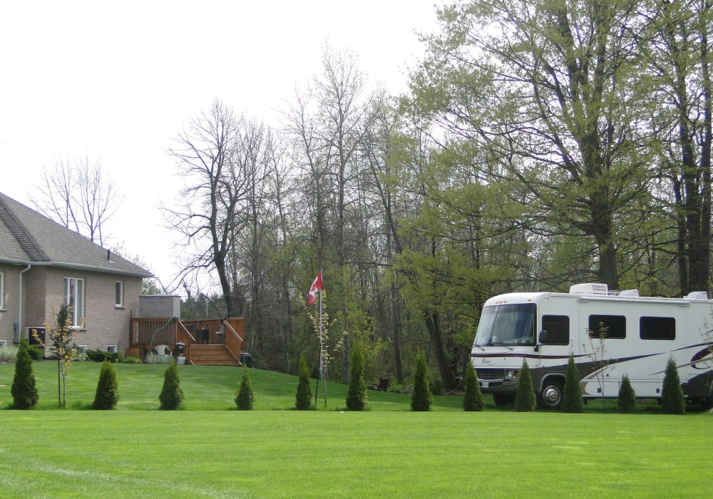 a freshly treated lawn, an RV in the background, and canadian flag